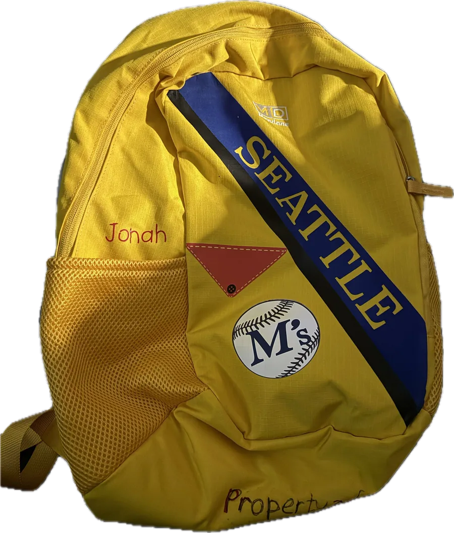 A yellow child's backpack personalized with a name and a Seattle Mariners baseball design.