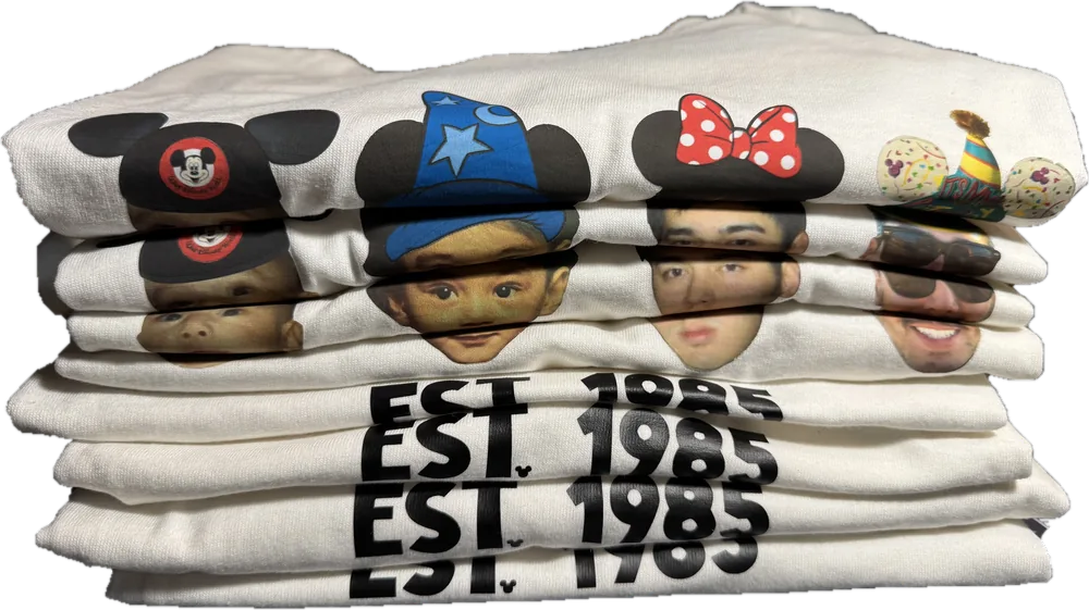 A folded stack of identical matching tees, each printed with the same four faces and the words EST. 1985.