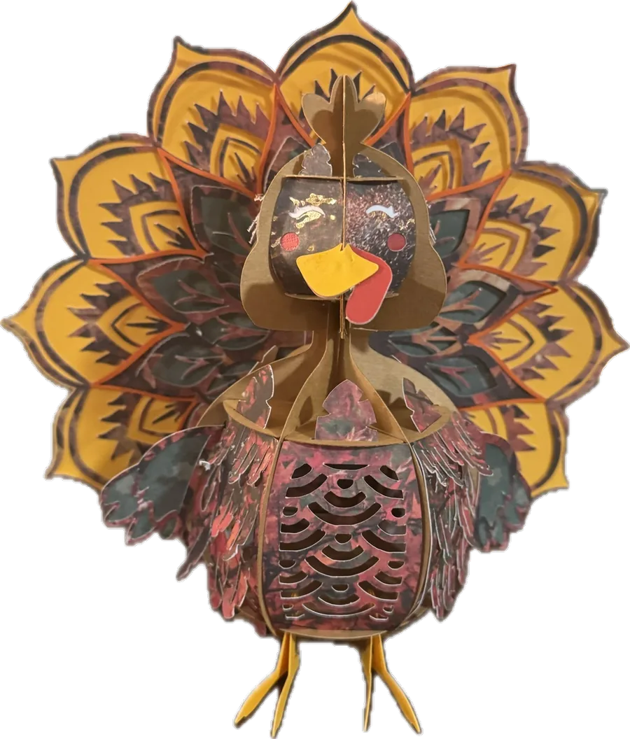 A layered paper turkey sculpture with a fanned tail, built from cut and stacked patterned paper.