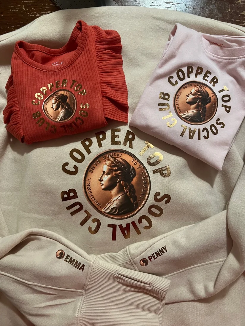 Three matching sweatshirts in red, pink and cream, printed with a club crest and names stitched on the cuffs.