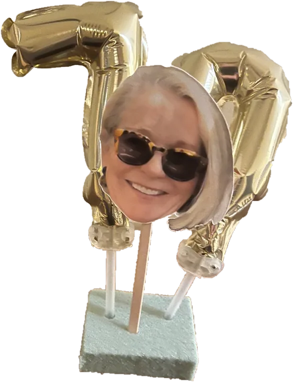A birthday cake topper: gold foil balloons on sticks mounted in a small base, with a cut-out photograph between them.