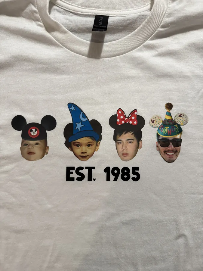 A white tee printed with four photographed faces wearing different novelty ears, above the words EST. 1985.