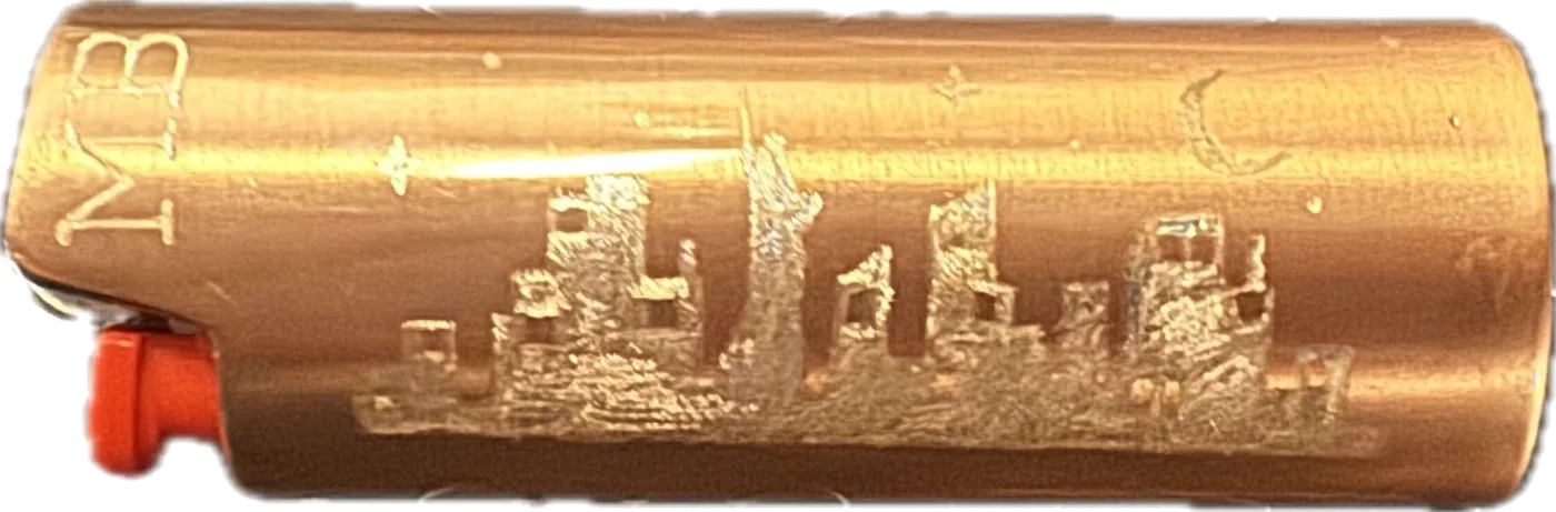 A copper lighter engraved by hand with the New York City skyline and a set of initials.